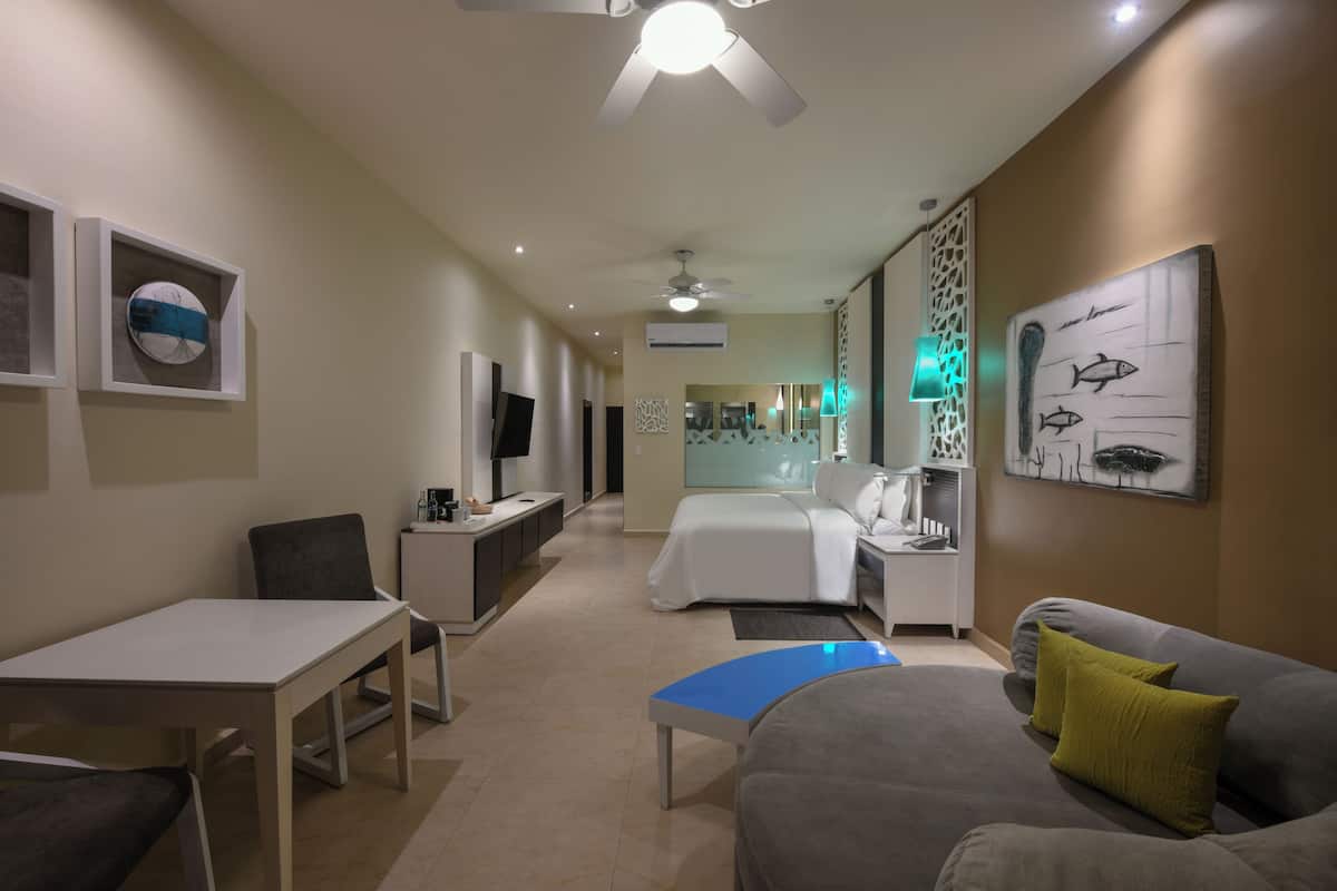 Una habitación de hotel con cama, escritorio, silla, sofá y televisión.