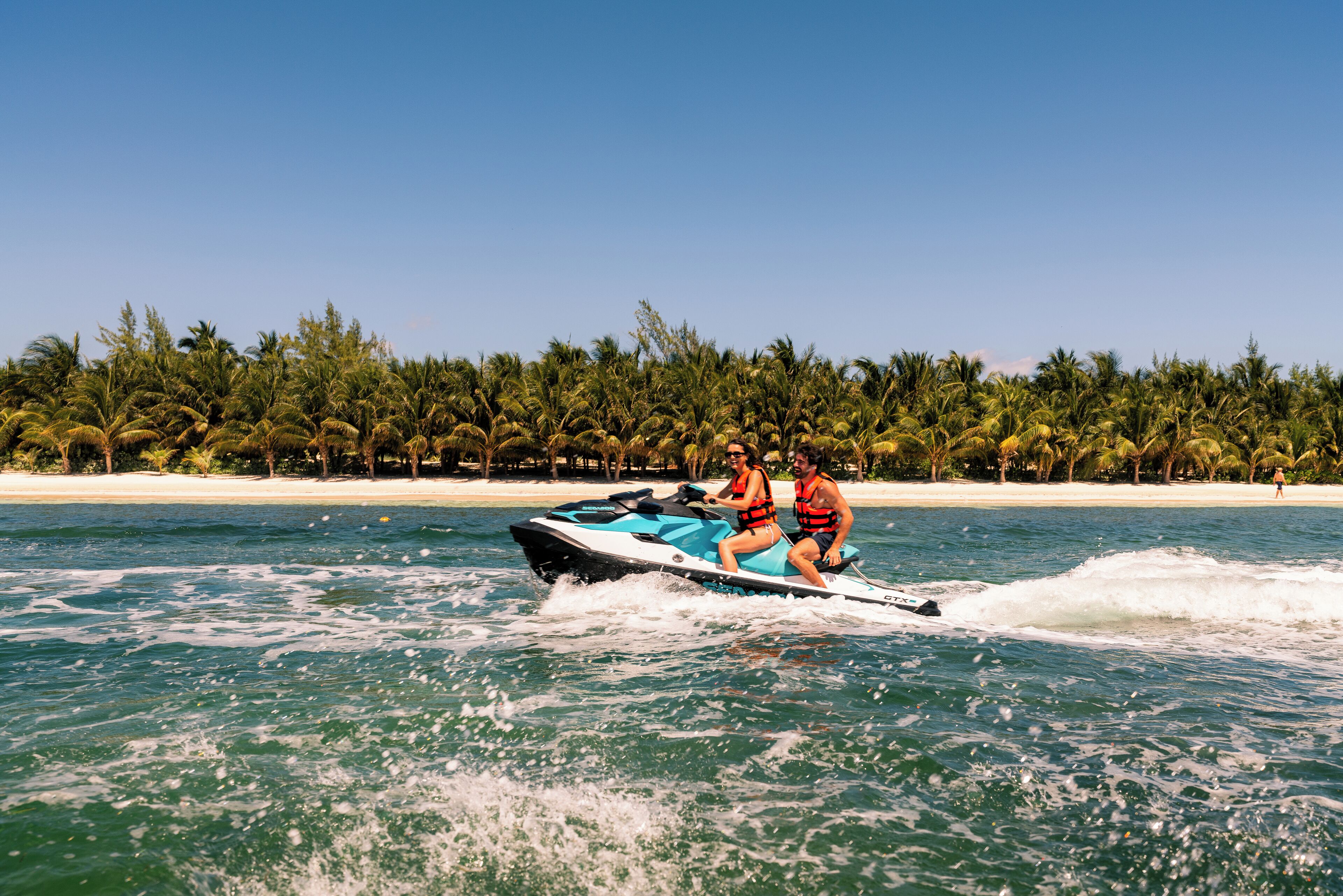 A jet ski on a clear day with a beach and palm trees in the background.