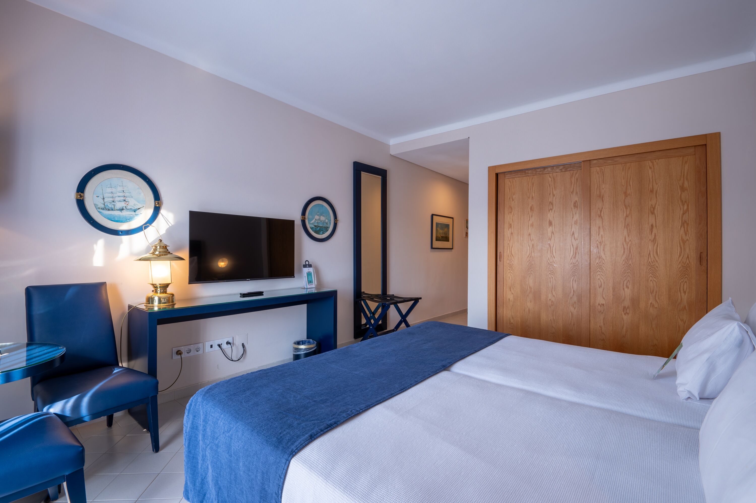 Une chambre d’hôtel avec un lit, un bureau avec une télévision, une chaise et une petite table.