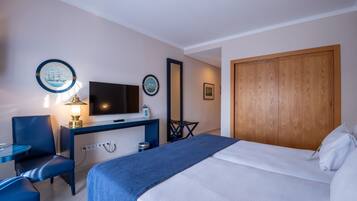 Une chambre d’hôtel avec un lit, un bureau avec une télévision, une chaise et une petite table.