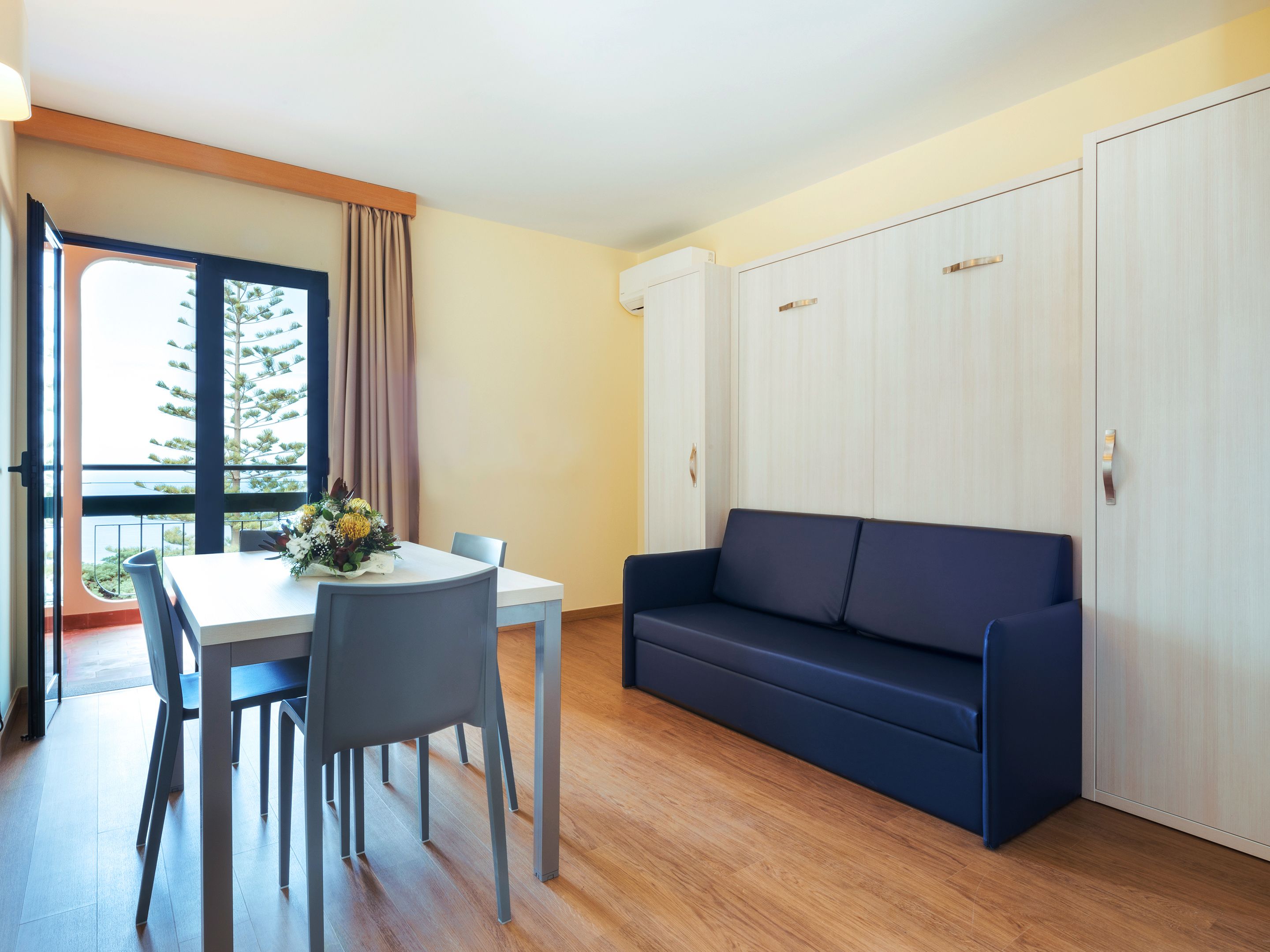 Une pièce moderne comprenant une table à manger, des chaises, un canapé et un placard à portes coulissantes.
