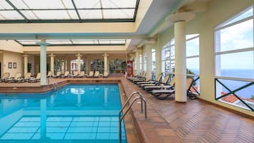 Una piscina interior con sillones de descanso y vistas al océano.