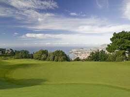 Un campo de golf con vista a una ciudad costera en la distancia.
