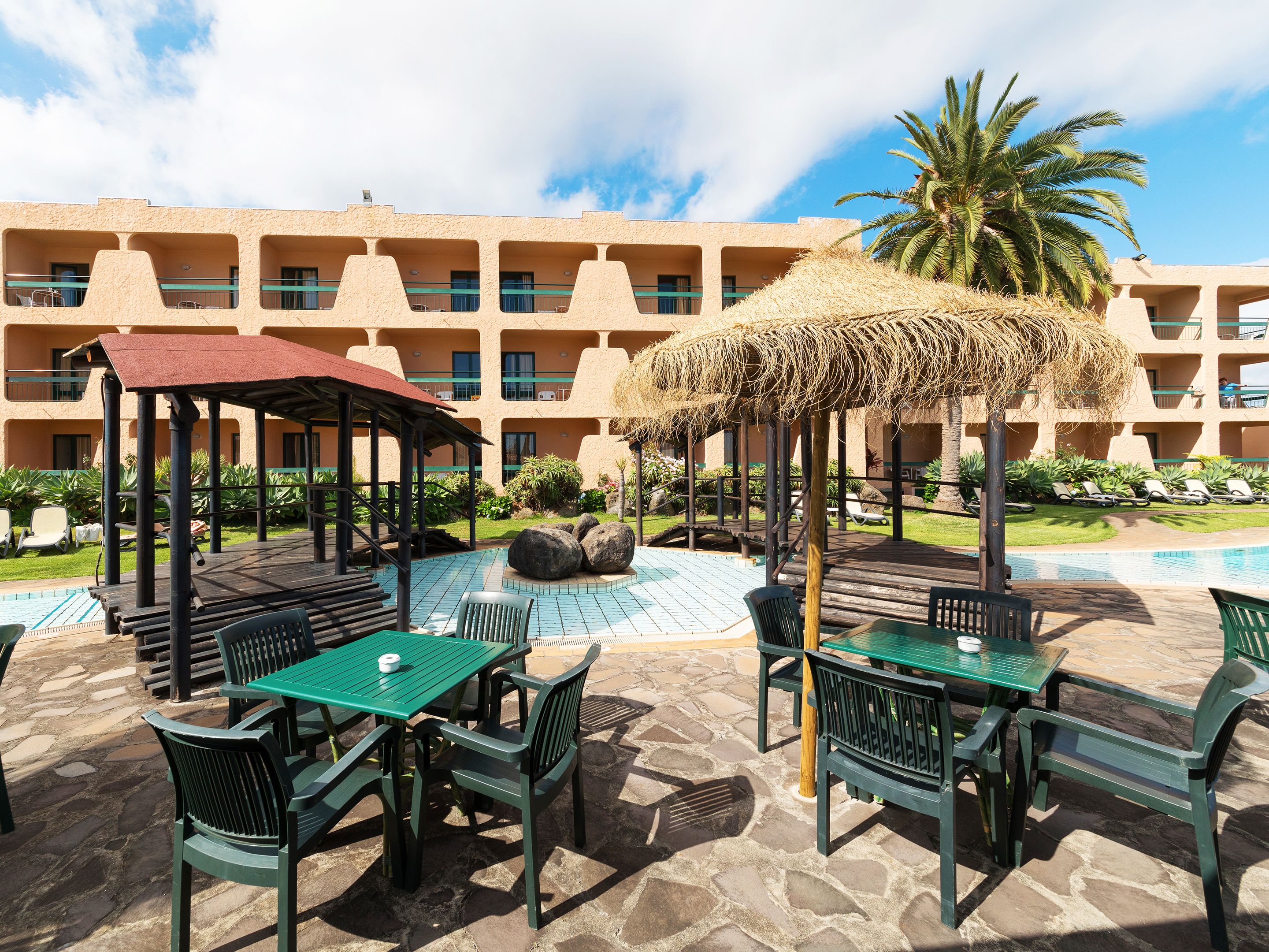 Ein Resort mit Poolbereich, Außenbereich zum Sitzen und einem Gebäude mit mehreren Balkonen.