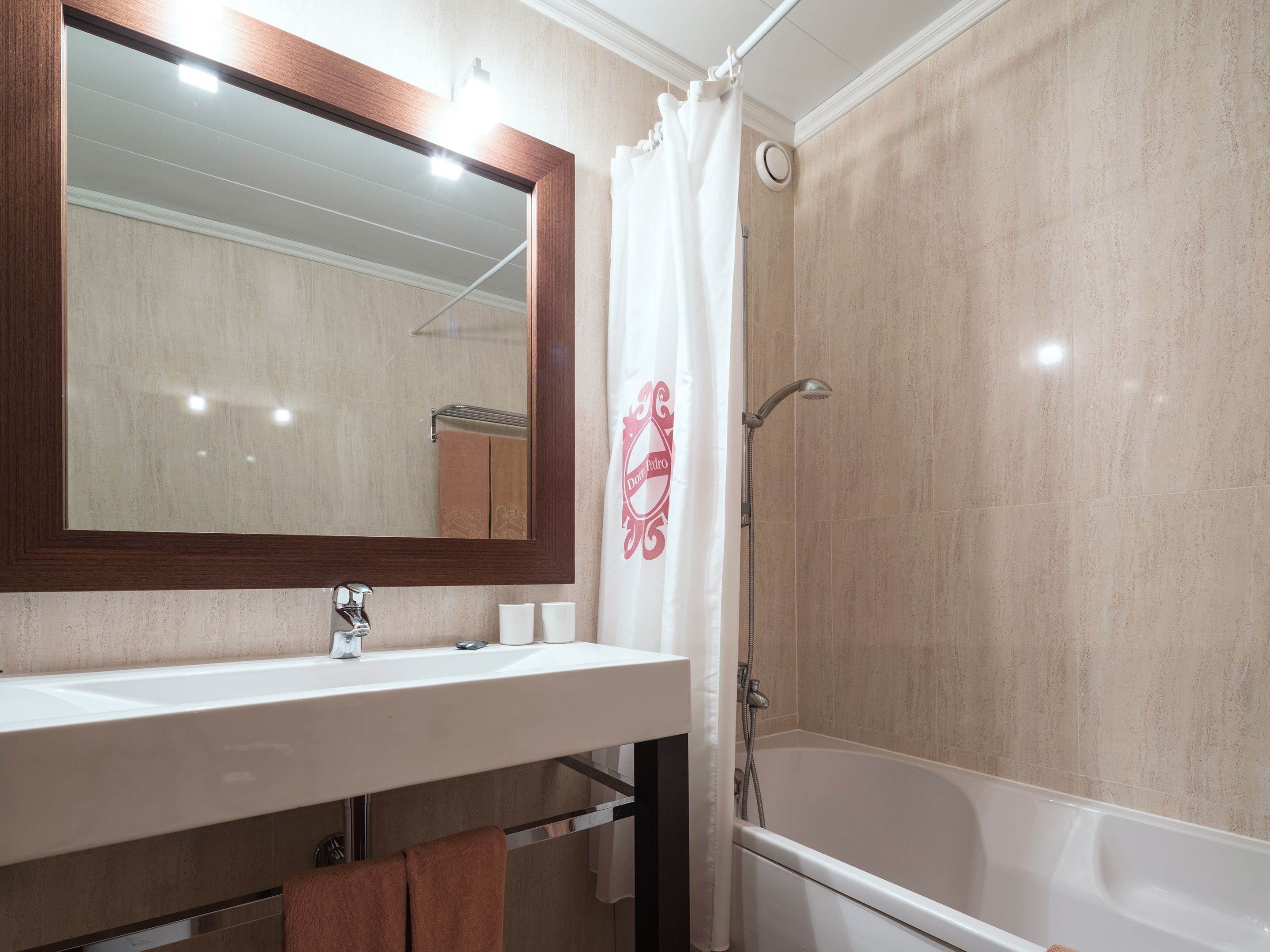 A bathroom with a white sink, mirror, and shower.