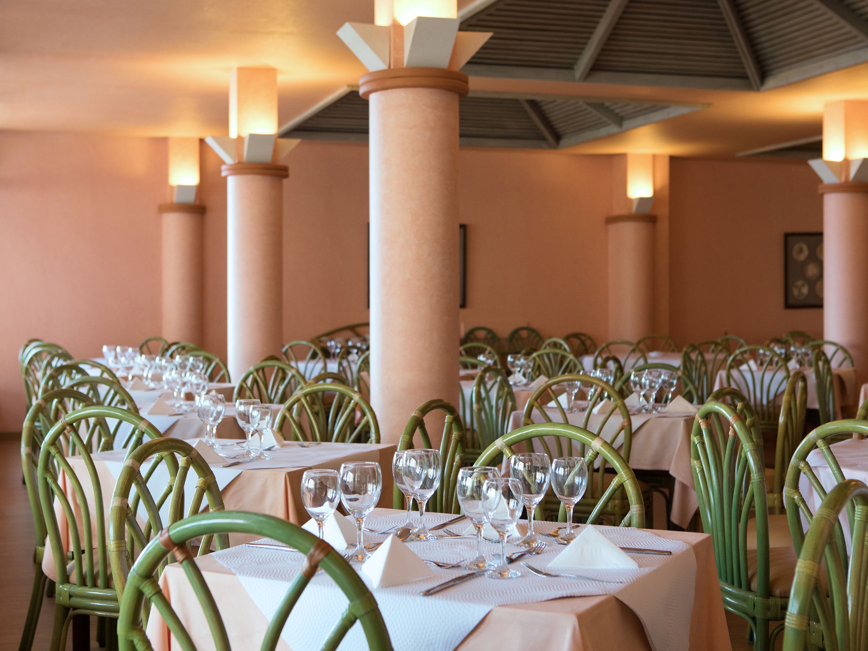 Un restaurant avec de nombreuses tables dressées pour le service, chacune étant équipée de chaises et de verres.