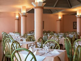 Un restaurant avec de nombreuses tables dressées pour le service, chacune étant équipée de chaises et de verres.