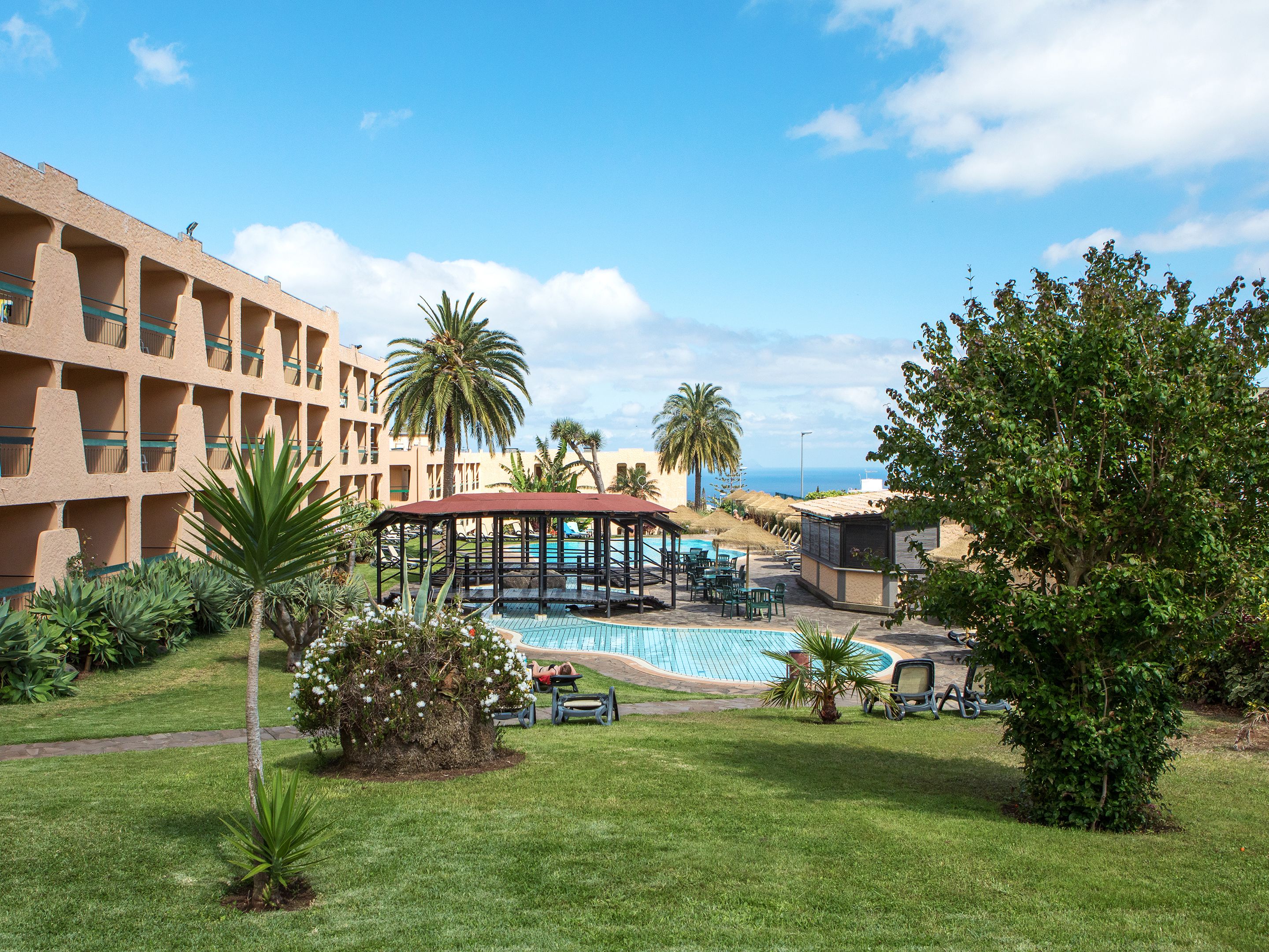 A resort with a pool area, palm trees, and a building with balconies.
