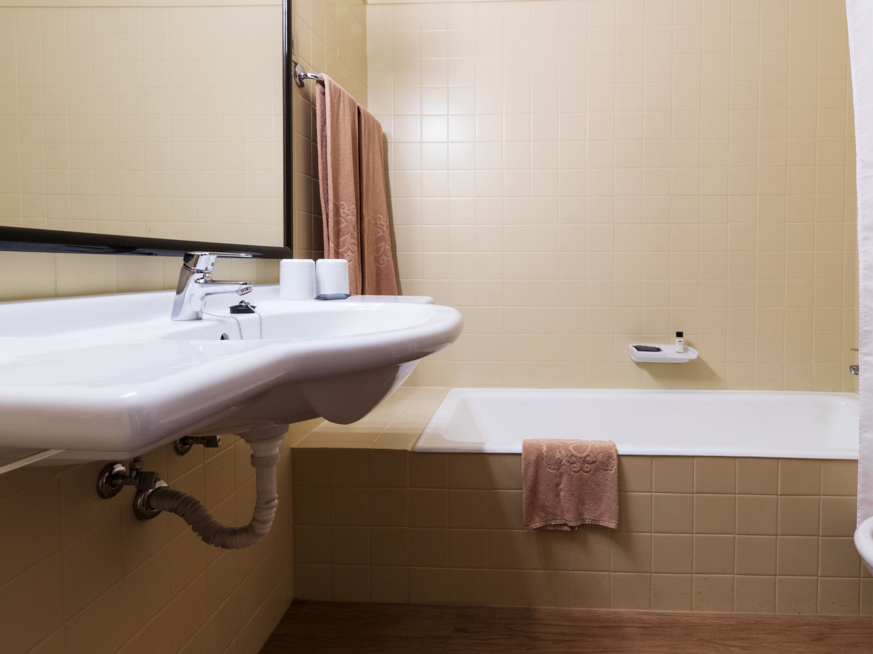 Une salle de bain équipée d’un lavabo, d’un miroir, d’un porte-serviettes et d’une baignoire.