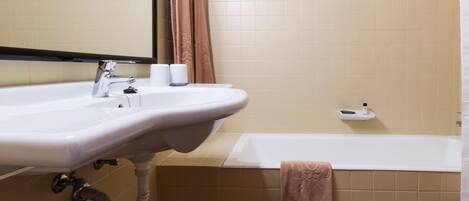 A bathroom with a sink, mirror, towel rack, and bathtub.