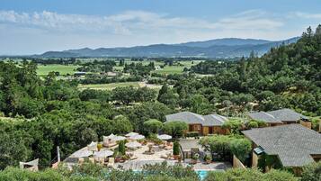 A resort with multiple villas, a swimming pool, and a view of the surrounding countryside.