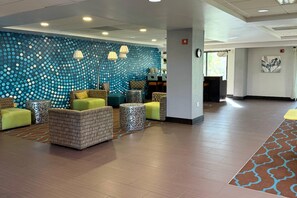 Un hall d’entrée avec un mur décoré de motifs, un espace détente avec des coussins et une moquette à motifs.