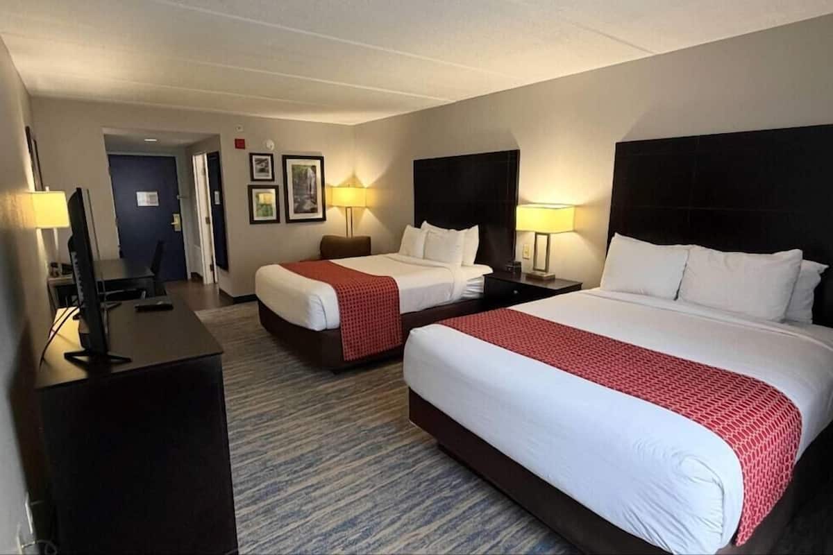 A hotel room with two beds, a desk with a computer, and a TV.