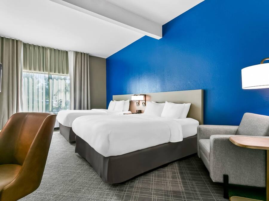 A hotel room with a large bed, two bedside tables, a desk, a chair, and a TV.