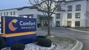 A sign for a Comfort Inn & Suites hotel with a parking lot and a building in the background. - Comfort Inn & Suites Grand Blanc/Flint (Grand Blanc)