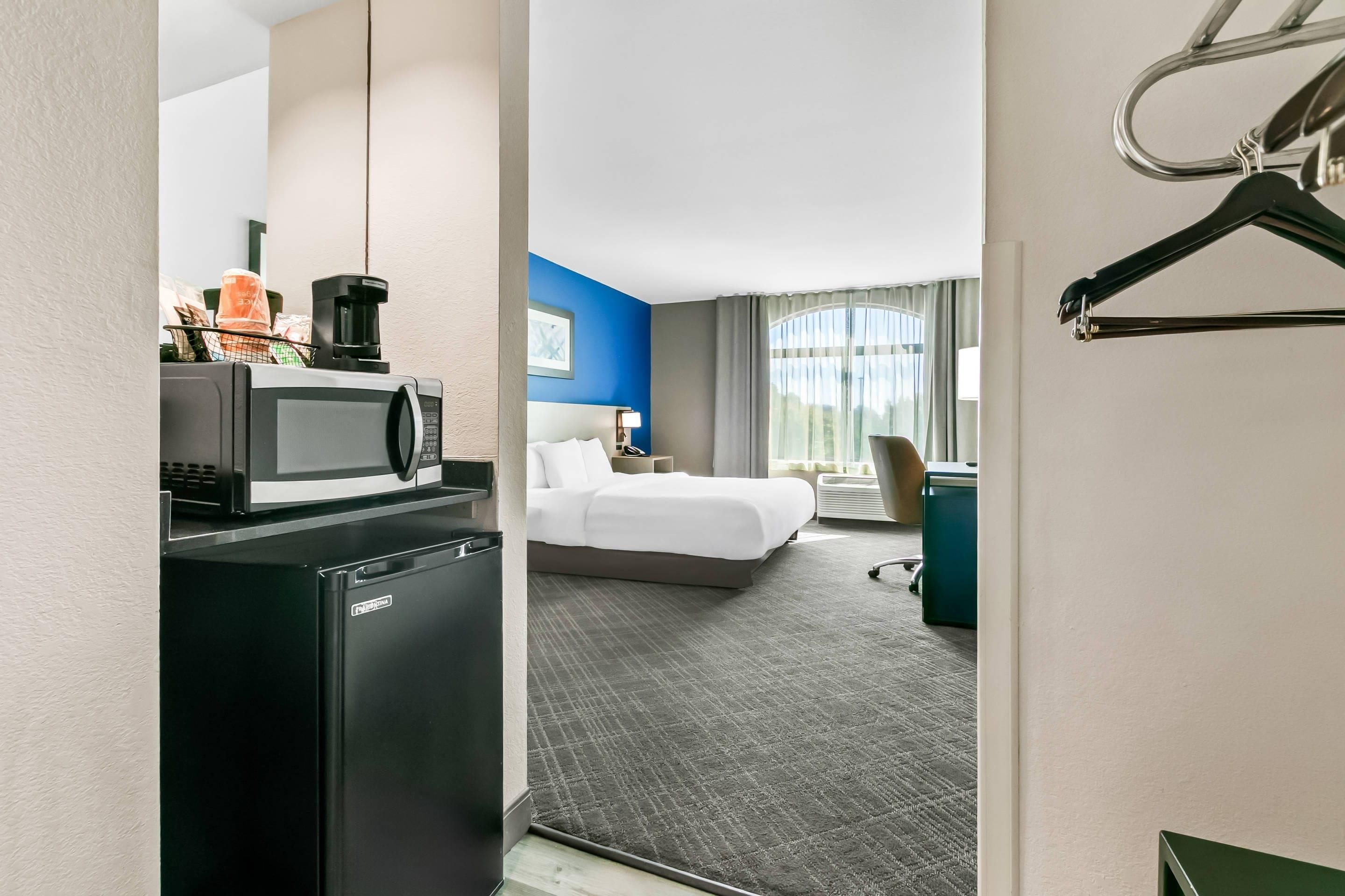 Une chambre d’hôtel équipée d’un lit, d’un bureau avec un ordinateur, d’un four à micro-ondes et d’un réfrigérateur.
