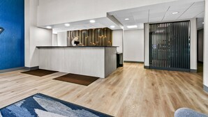 A modern reception area with a wooden reception desk, recessed lighting, and a blue accent wall. - Comfort Inn & Suites Grand Blanc/Flint (Grand Blanc)