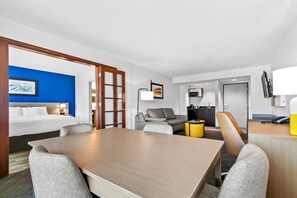 A hotel room with a bed, a dining table, a sofa, and a TV. - Comfort Inn & Suites Grand Blanc/Flint (Grand Blanc)