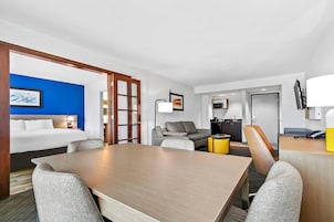 Una habitación de hotel con cama, mesa de comedor, sofá y televisión.