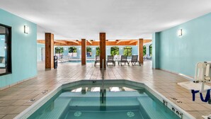 An indoor swimming pool with clear water, wooden pillars, and lounge chairs. - Comfort Inn & Suites Grand Blanc/Flint (Grand Blanc)