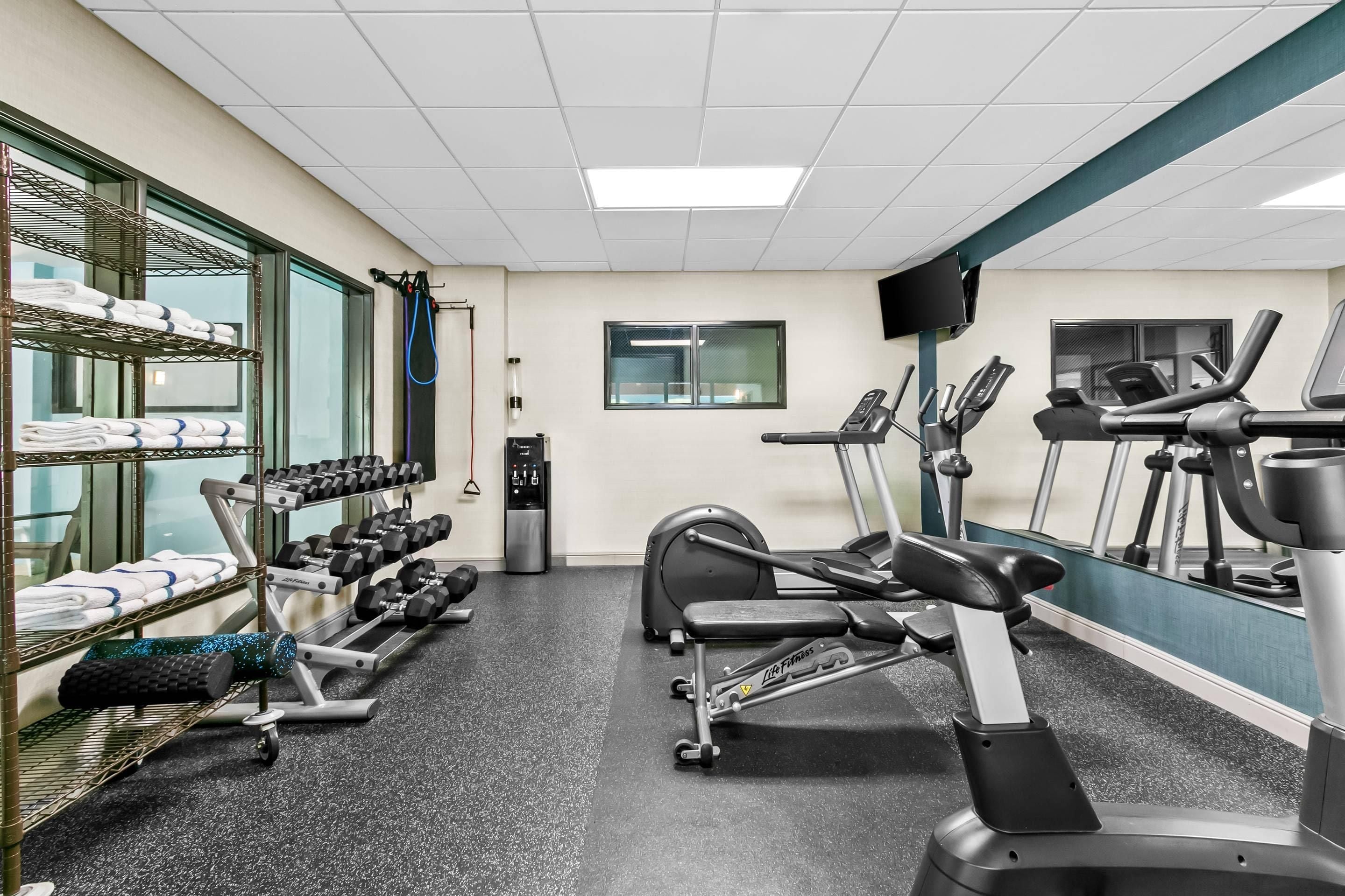 Een sportschool met trainingsapparatuur, loopband en een halterrek.
