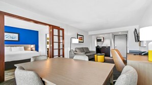 A hotel room with a bed, a dining table, a sofa, and a TV. - Comfort Inn & Suites Grand Blanc/Flint (Grand Blanc)