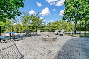 Un patio al aire libre con una chimenea, mesas de picnic y sillas Adirondack.