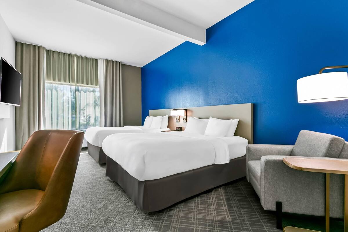 A hotel room with a large bed, two bedside tables, a desk, a chair, and a TV.