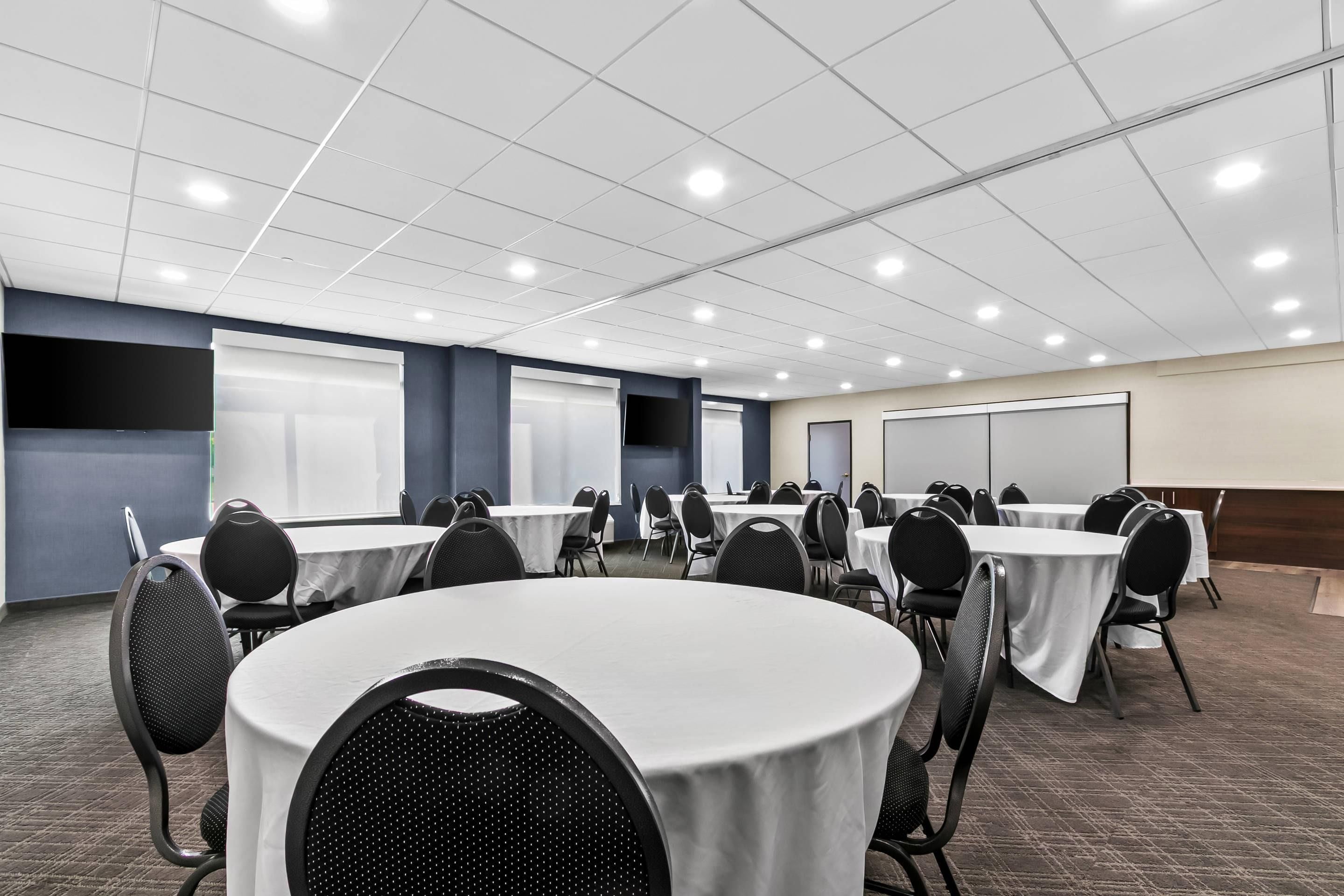 A conference room with round tables, chairs, and a whiteboard.