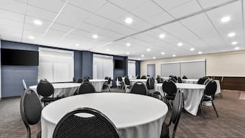 A conference room with round tables, chairs, and a whiteboard.