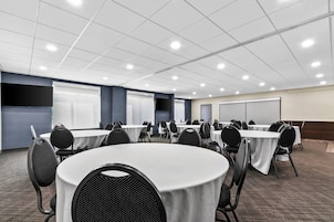 Un salón de conferencias con mesas redondas, sillas y una pizarra.