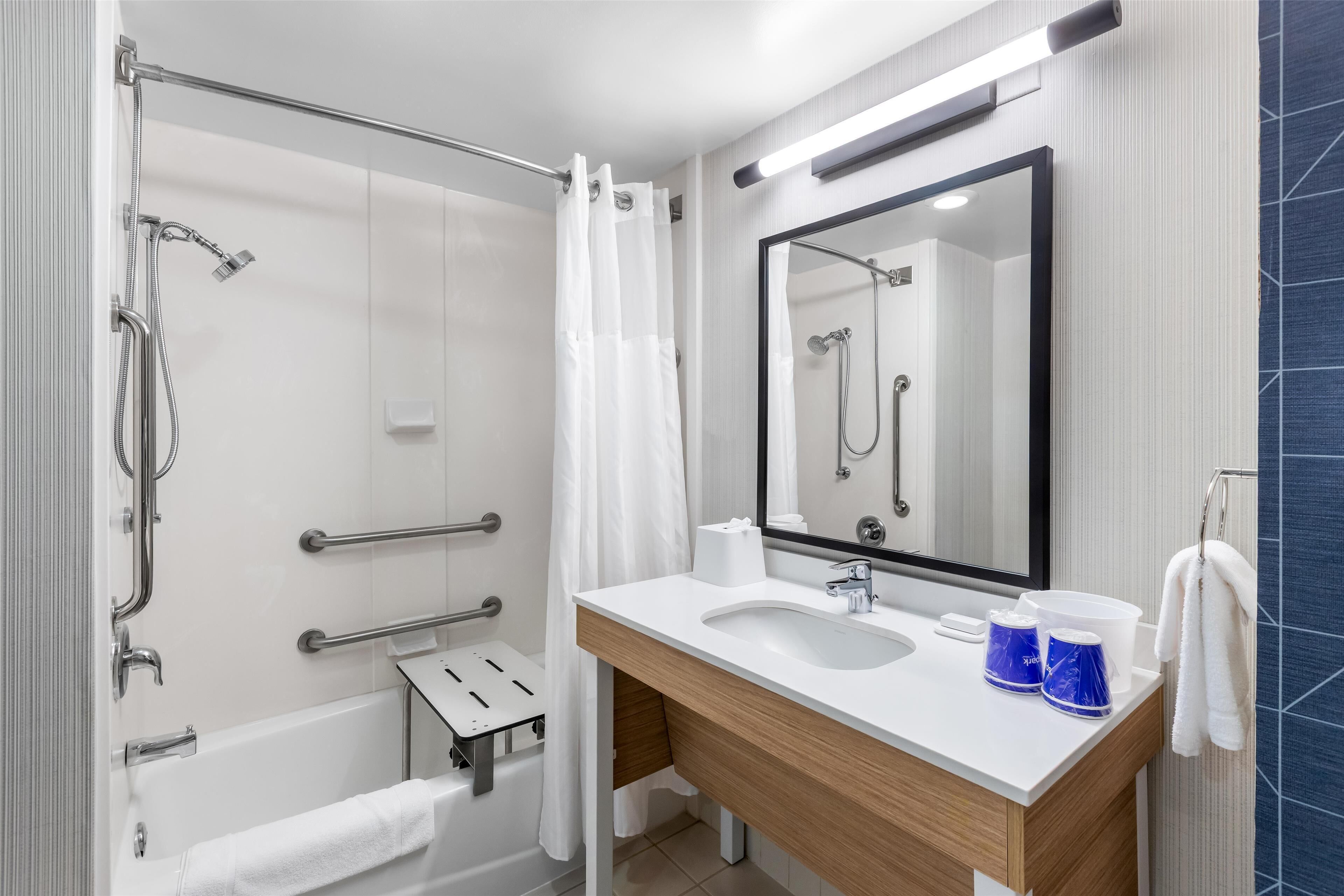 A modern bathroom with a shower, a sink, and a mirror.