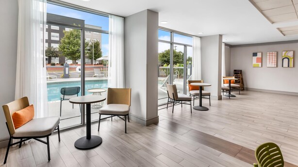 Un espacio interior amplio con ventanas grandes, vista a la piscina y varios conjuntos de asientos.