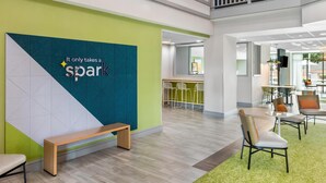 Un espacio interior moderno con una paleta de colores verde y blanco, un banco y una zona de estar con sillas.