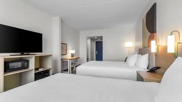 Habitació d'hotel amb dos llits, un escriptori amb cadira, televisió, microones i telèfon.