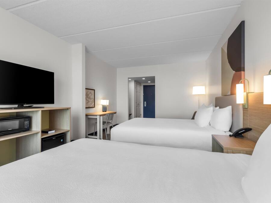 Habitació d'hotel amb dos llits, un escriptori amb cadira, televisió, microones i telèfon.