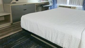Una habitación de hotel con una cama, un escritorio, un televisor de pantalla plana, una lámpara y una ventana con cortinas.