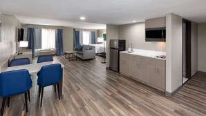 A modern hotel room with a dining area, kitchenette, and a living space.