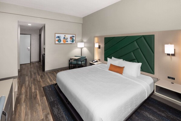Habitación de hotel con una cama grande, un escritorio, una silla y un cuadro en la pared.