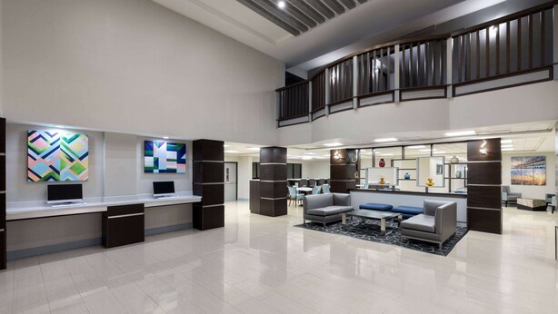A spacious lobby with a high ceiling, modern furniture, and artwork on the walls.