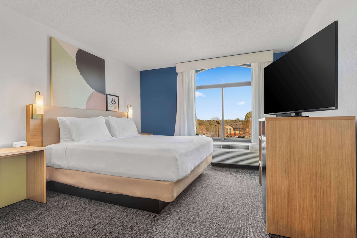 Ein Hotelzimmer mit Bett, Schreibtisch, Fernseher und einem großen Fenster mit Blick.