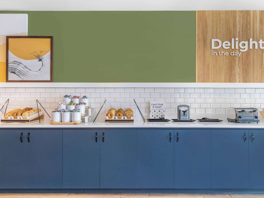 A modern kitchen with a blue cabinet, white tiles, and a wooden accent wall.