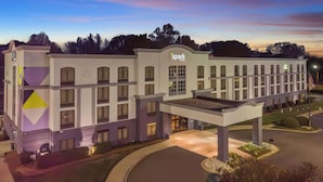 A hotel with a modern design, featuring a prominent 'Spark' sign, multiple windows, and a well-lit entrance area. - Spark by Hilton Charlotte Tyvola I-77 (Charlotte)