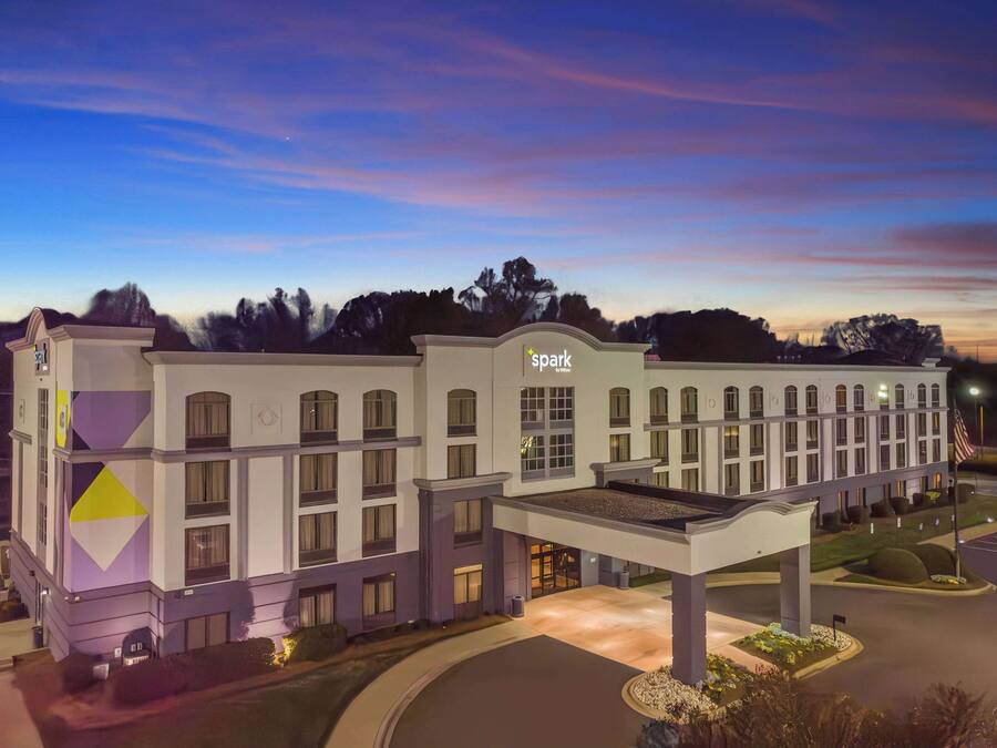Un hotel dal design moderno, con un cartello 'Spark' ben visibile, diverse finestre e un'area d'ingresso ben illuminata.