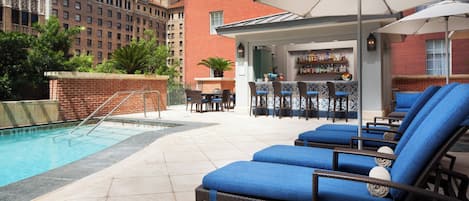 Un área junto a la piscina con sillones de descanso, un bar y una pileta.