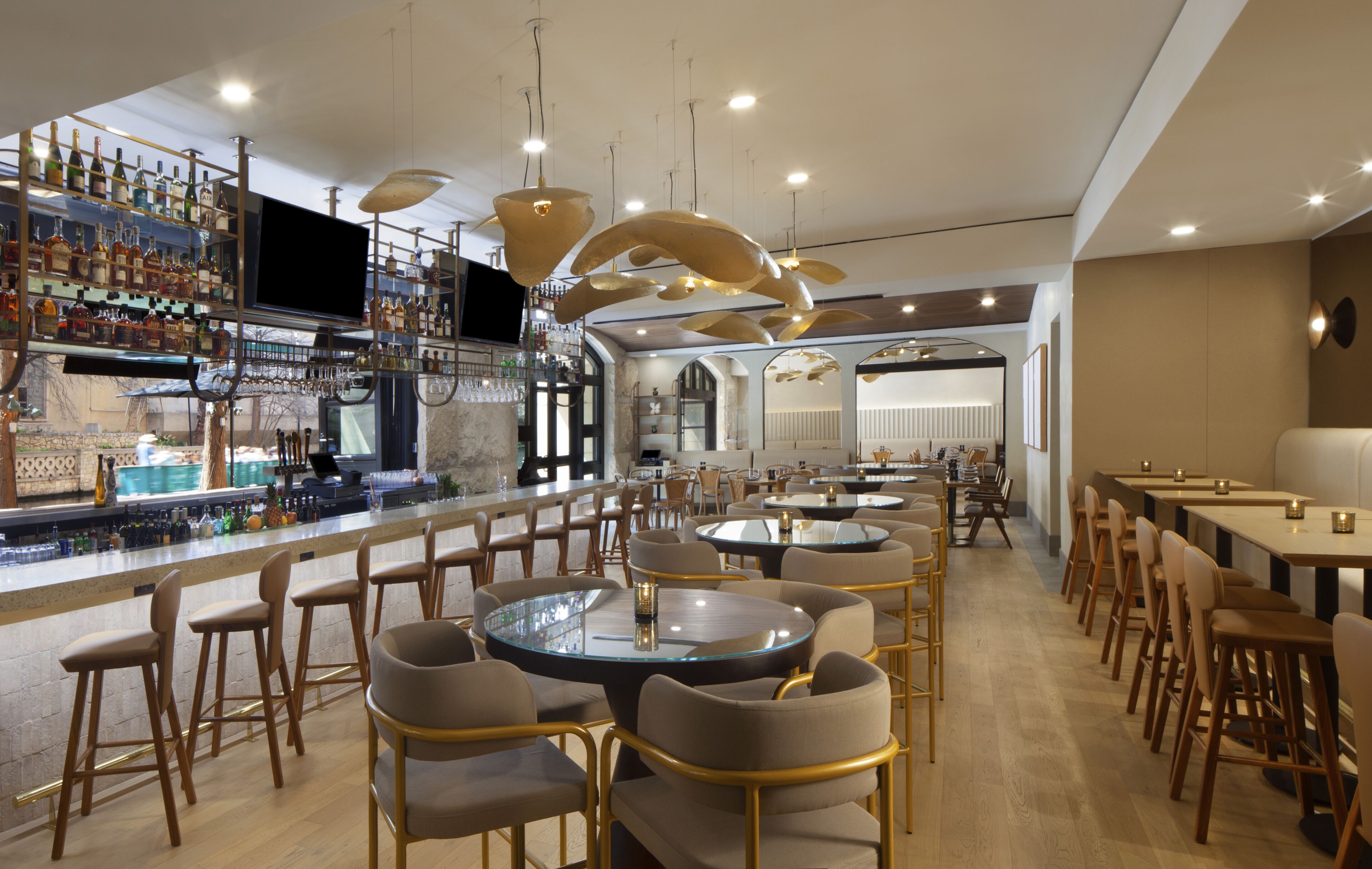 A bar area with multiple seating options, a television, and a variety of bottles on shelves.