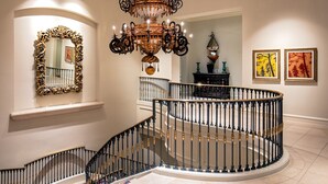 A grand staircase with ornate black railings and a chandelier.