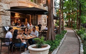 An outdoor dining area with tables and chairs, surrounded by greenery and trees. - The Westin Riverwalk, San Antonio (San Antonio)