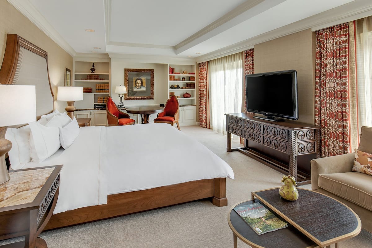 Een hotelkamer met een groot bed, een televisie, een bureau en een stoel.