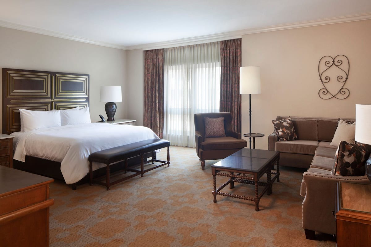 Een hotelkamer met een bed, een bureau, een stoel, een bank en een lamp.